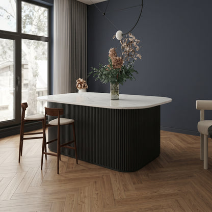 Black flexible fluted reeded acoustic tambour panel wrapped around a curved island counter, dark navy wall